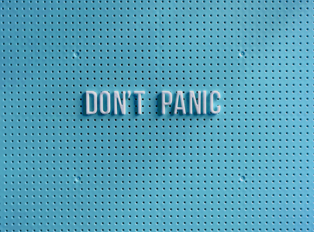 Schriftzug „Don’t Panic“ auf blauer Lochwand